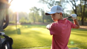 Young student in golf stance at driving range, concentrated expression, morning sunlight filtering through trees, outdoor practice environment with manicured grass